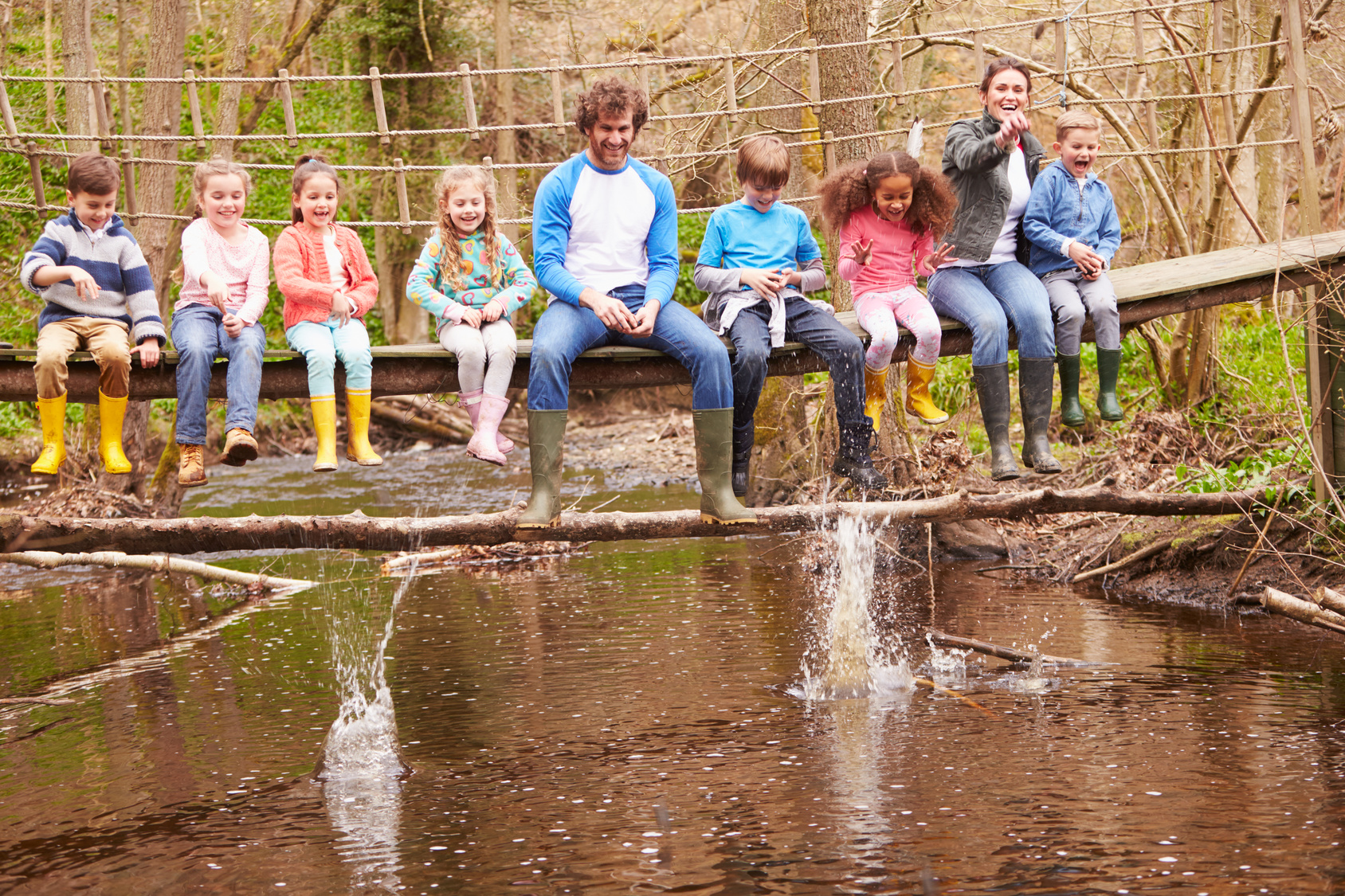 Adults With Children On Bridge At Outdoor Activity Centre
