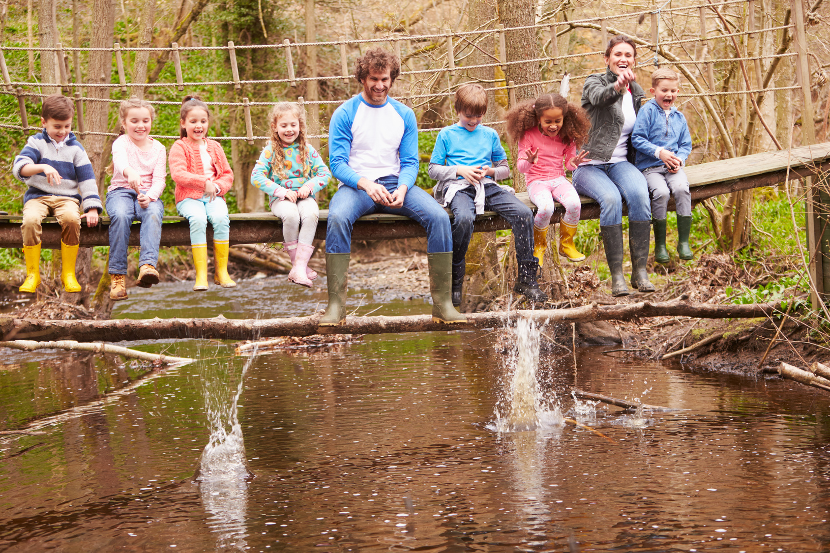 Adults With Children On Bridge At Outdoor Activity Centre